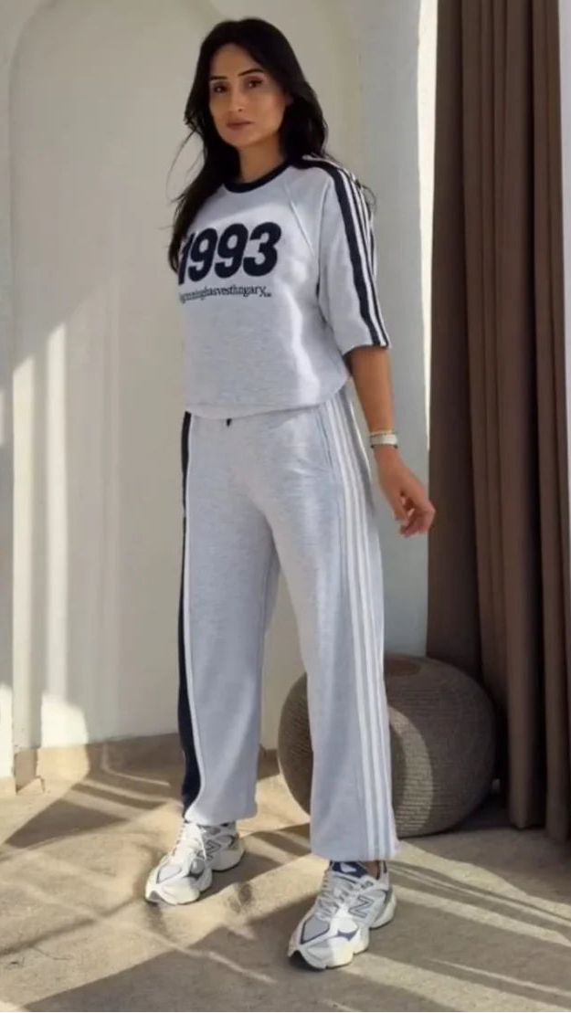 Grey 1993 graphic sweatshirt and matching wide-leg track pants set paired with white chunky sneakers 01
