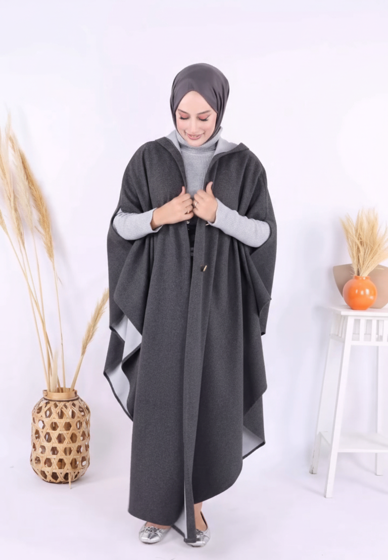 Woman wearing a dark gray abaya with a white background