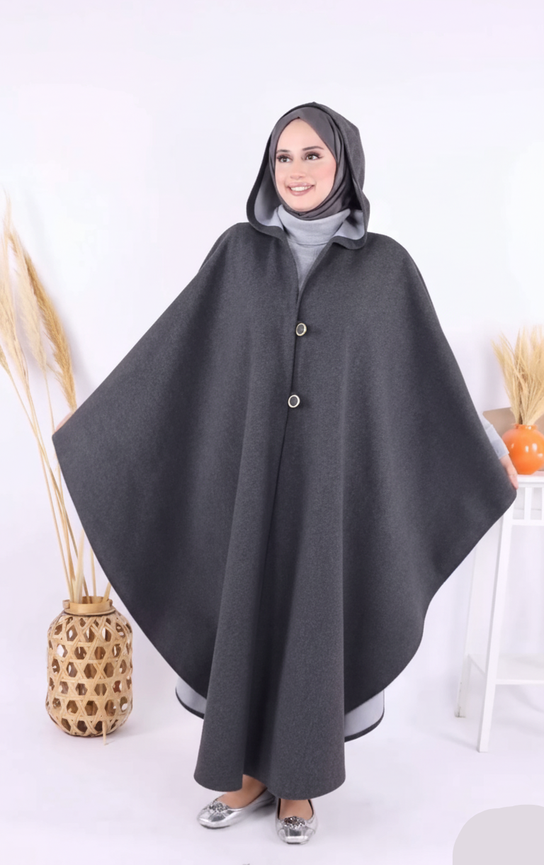Woman wearing a gray poncho with a hood on a white background