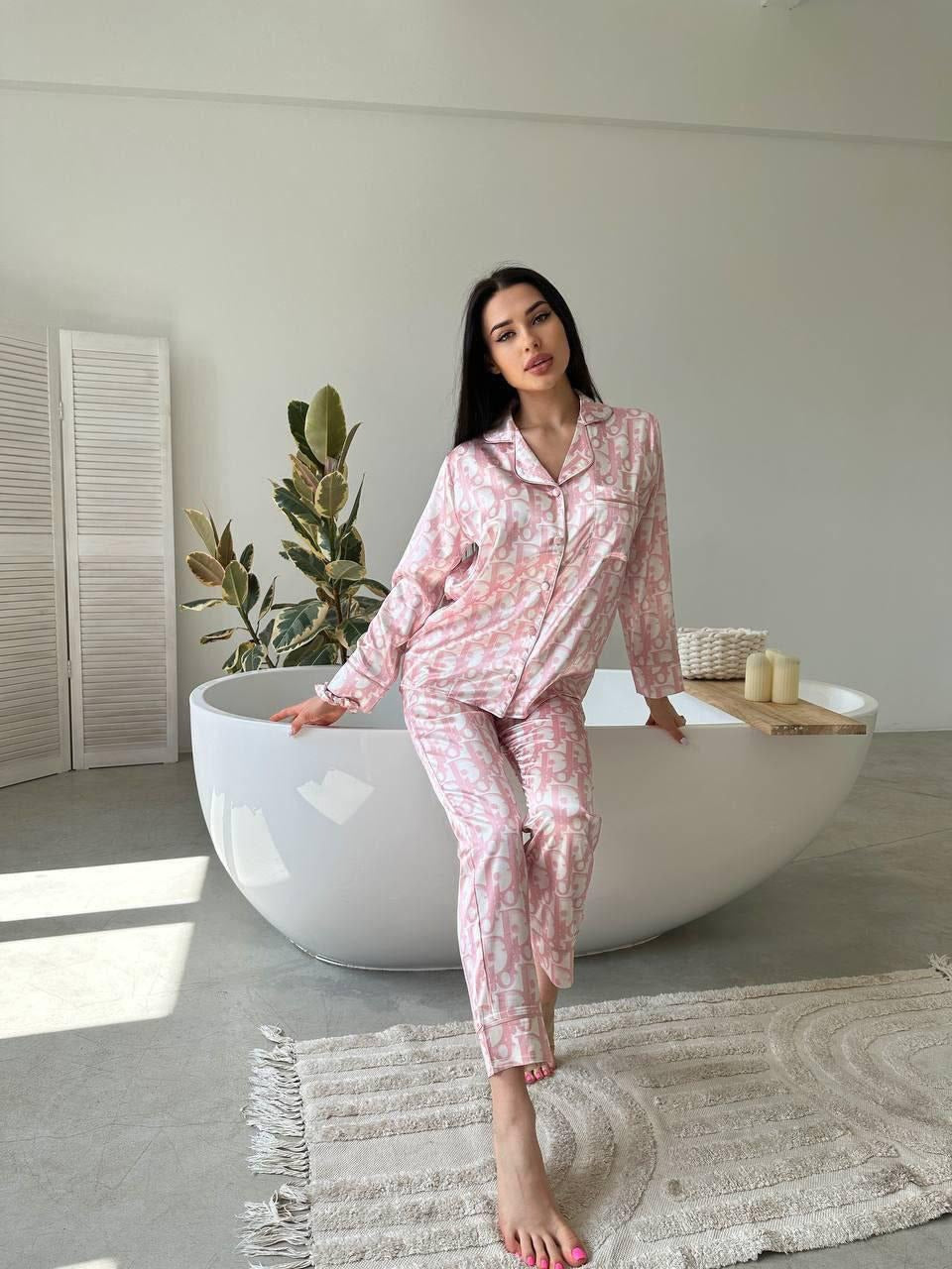 Woman in pink pajama set standing by a white bathtub in a bright room.