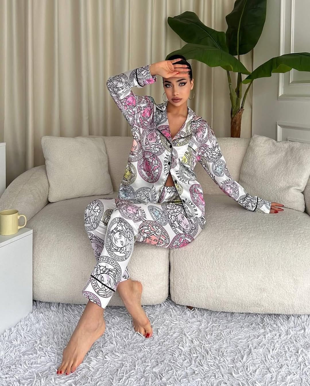 Woman in a patterned outfit sitting on a couch in a living room.