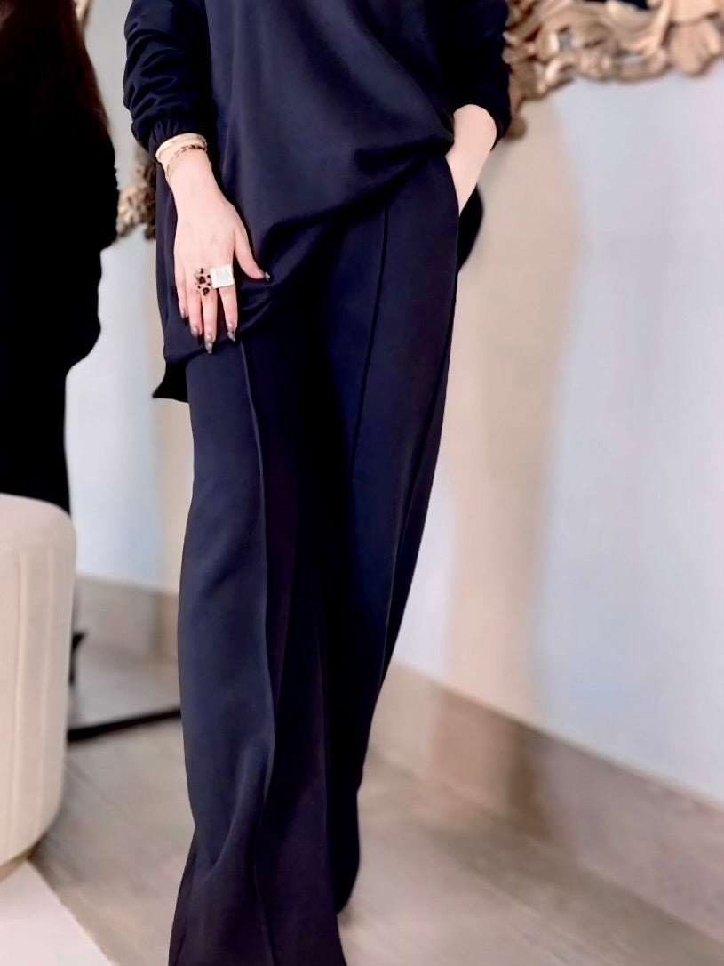 women wearing a dark outfit with wide-leg pants in an indoor setting