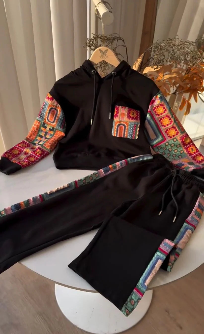 Black hoodie and pants with colorful geometric patterns on a white surface.