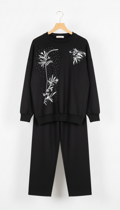 Black outfit with white floral embroidery on a white background