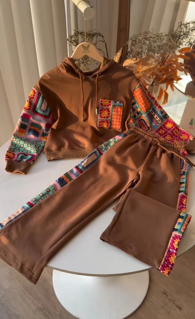 Camel_hoodie_and_pants_with_colorful_geometric_patterns_on_a_white_surface.