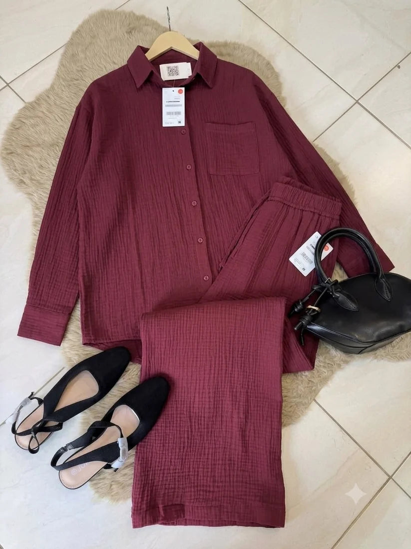Chakoor textured two-piece pajama set consisting of a long-sleeve button-up shirt and matching pants, styled in a flat lay with black shoes and a black handbag on a brown faux fur rug over a tiled floor. 014