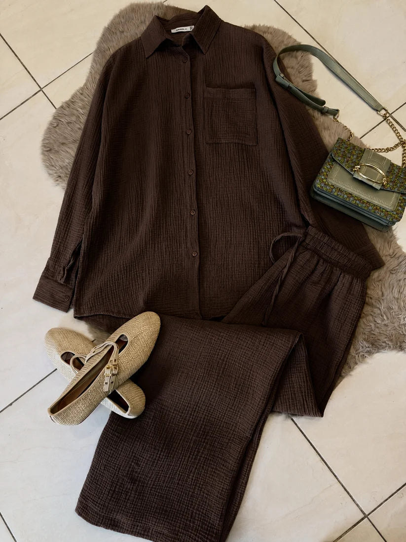 Chakoor textured two-piece pajama set consisting of a long-sleeve button-up shirt and matching pants, styled in a flat lay with black shoes and a black handbag on a brown faux fur rug over a tiled floor. 03