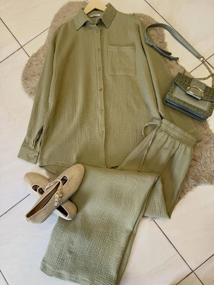 Chakoor textured two-piece pajama set consisting of a long-sleeve button-up shirt and matching pants, styled in a flat lay with black shoes and a black handbag on a brown faux fur rug over a tiled floor. 06