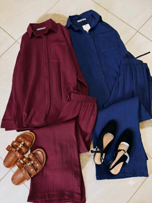 Chakoor textured two-piece pajama set consisting of a long-sleeve button-up shirt and matching pants, styled in a flat lay with black shoes and a black handbag on a brown faux fur rug over a tiled floor. 08