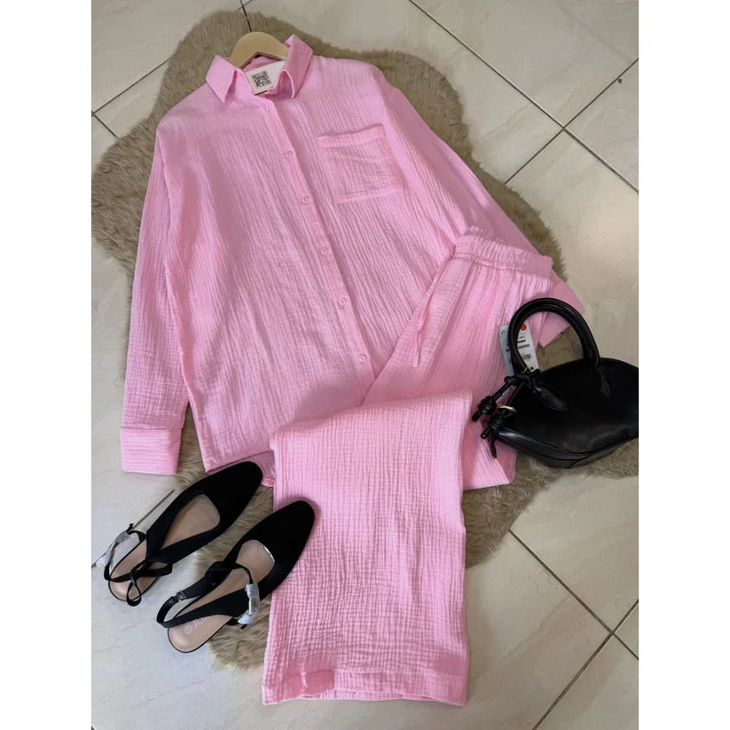 Chakoor textured two-piece pajama set consisting of a long-sleeve button-up shirt and matching pants, styled in a flat lay with black shoes and a black handbag on a brown faux fur rug over a tiled floor. 110