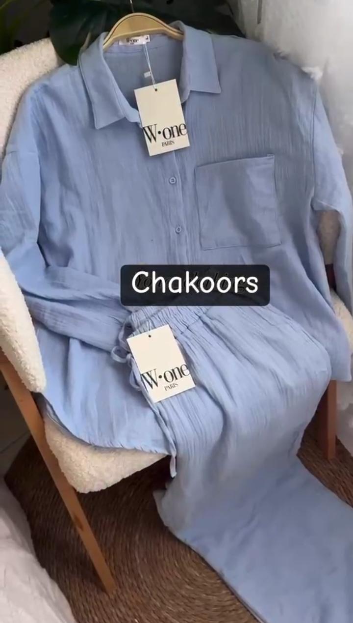 Minimalist two-piece shirt and trouser set with button-down top and elastic waist pants displayed on a chair with soft natural lighting, ideal for casual wear and everyday comfort 02