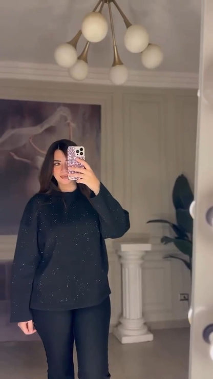 Person wearing a black outfit taking a mirror selfie in an indoor setting.