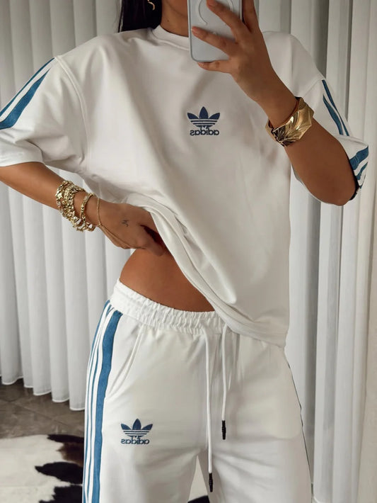 Stylish woman in black oversized co-ord set with striped track pants, sitting indoors and taking a mirror selfie. 06