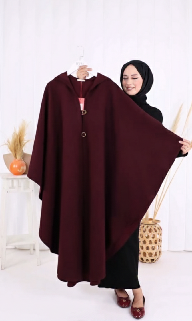 Woman holding a maroon poncho against a white background