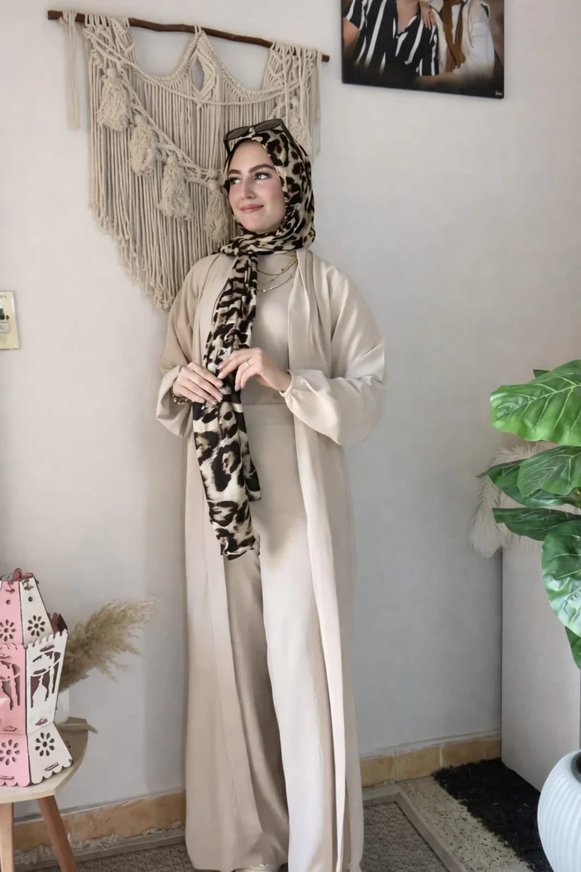 Woman wearing a chic beige three-piece modest ensemble with a long cardigan, wide-leg trousers, and a bold leopard print hijab 01