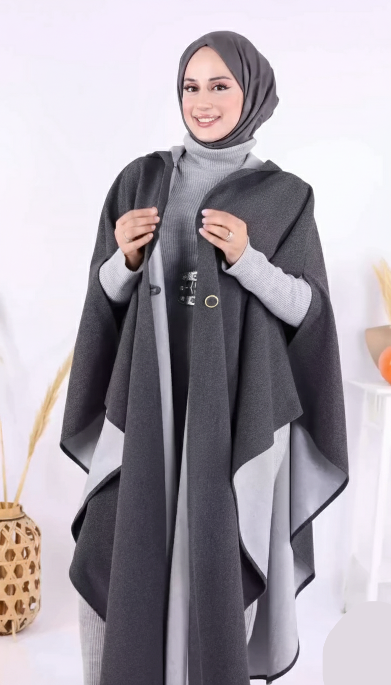 Woman wearing a gray poncho over a light gray outfit on a white background