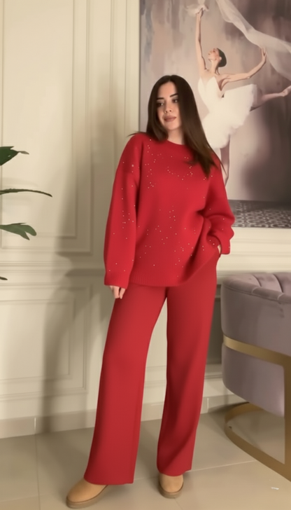 Woman wearing a red outfit standing in a room with a decorative wall and plant.