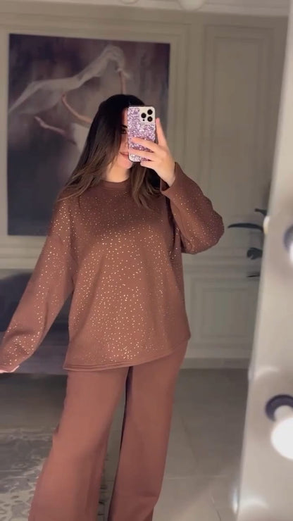Women wearing a brown outfit taking a mirror selfie in a room.