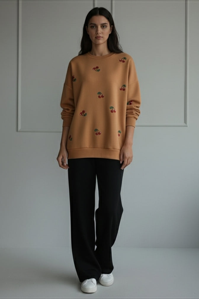 women winter 2026 wearing a brown sweater with floral patterns and black pants on a plain background